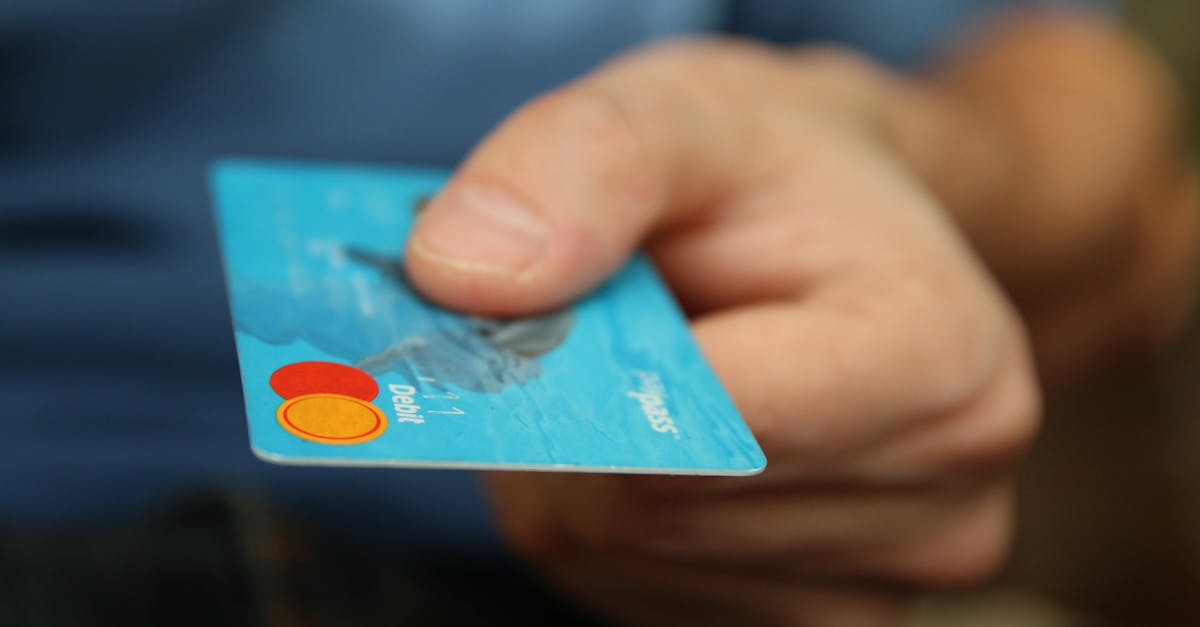a close up shot of a hand offering a blue debit card for payment